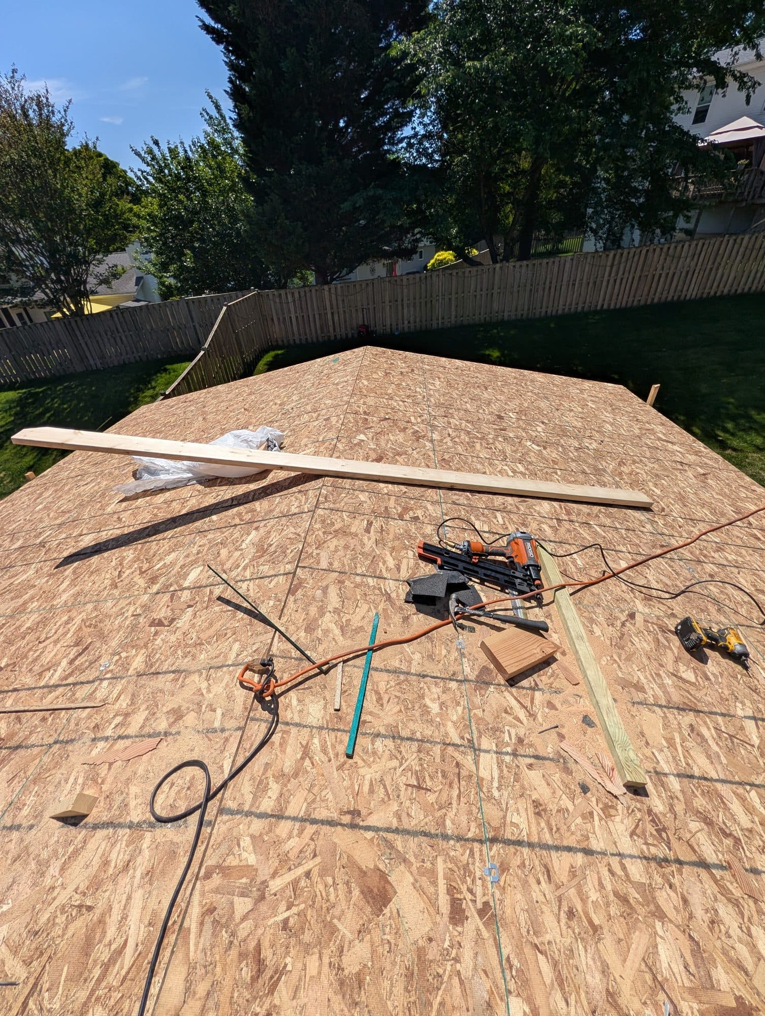New roof decking installed on a screened-in porch addition, ready for underlayment and shingles