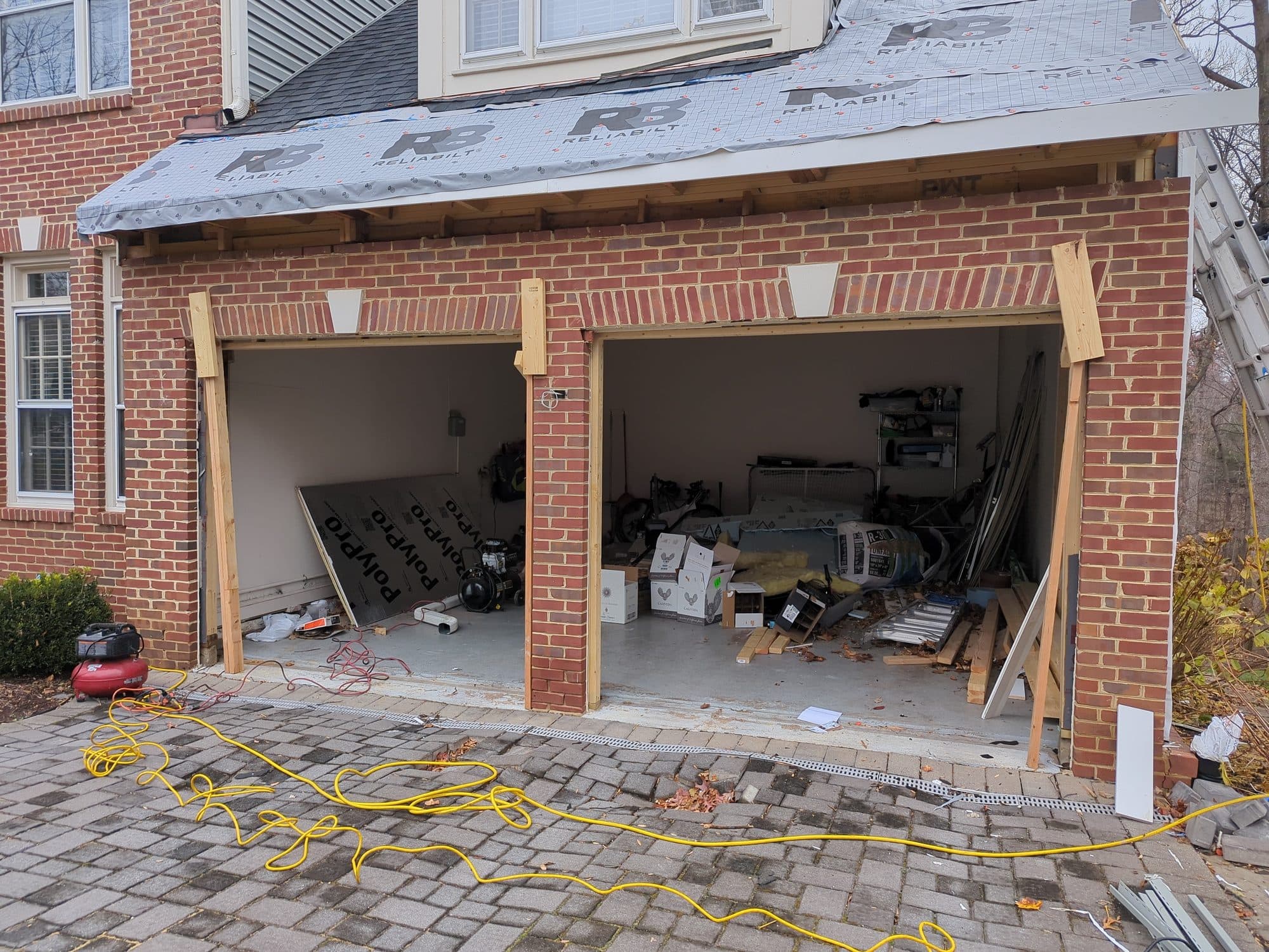 Garage under renovation with insulation board staged inside, new roof underlayment visible above