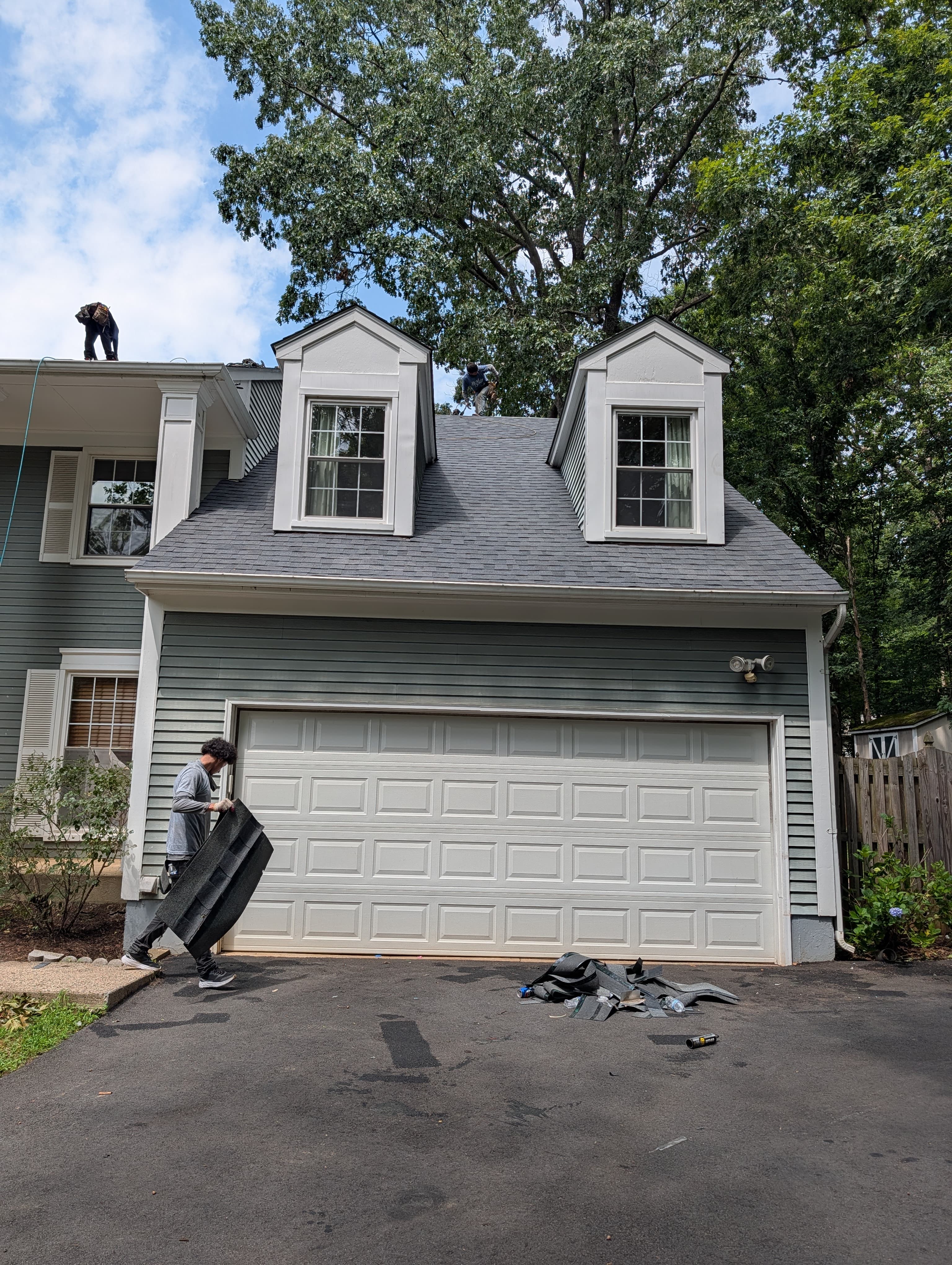 Roofers hauling old shingles off the roof during tear-off