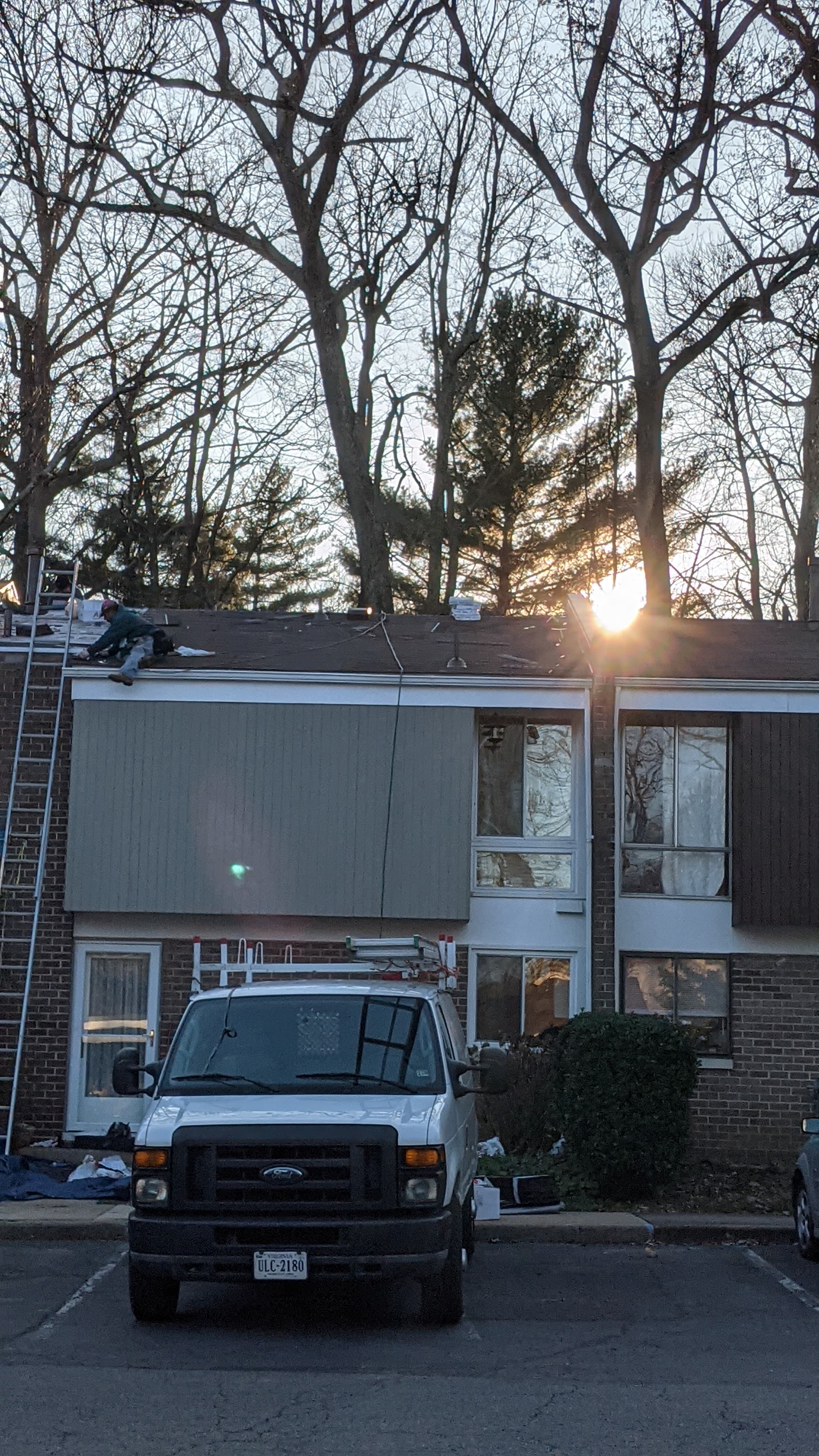 Roofer installing shingles during a full roof replacement in Sterling