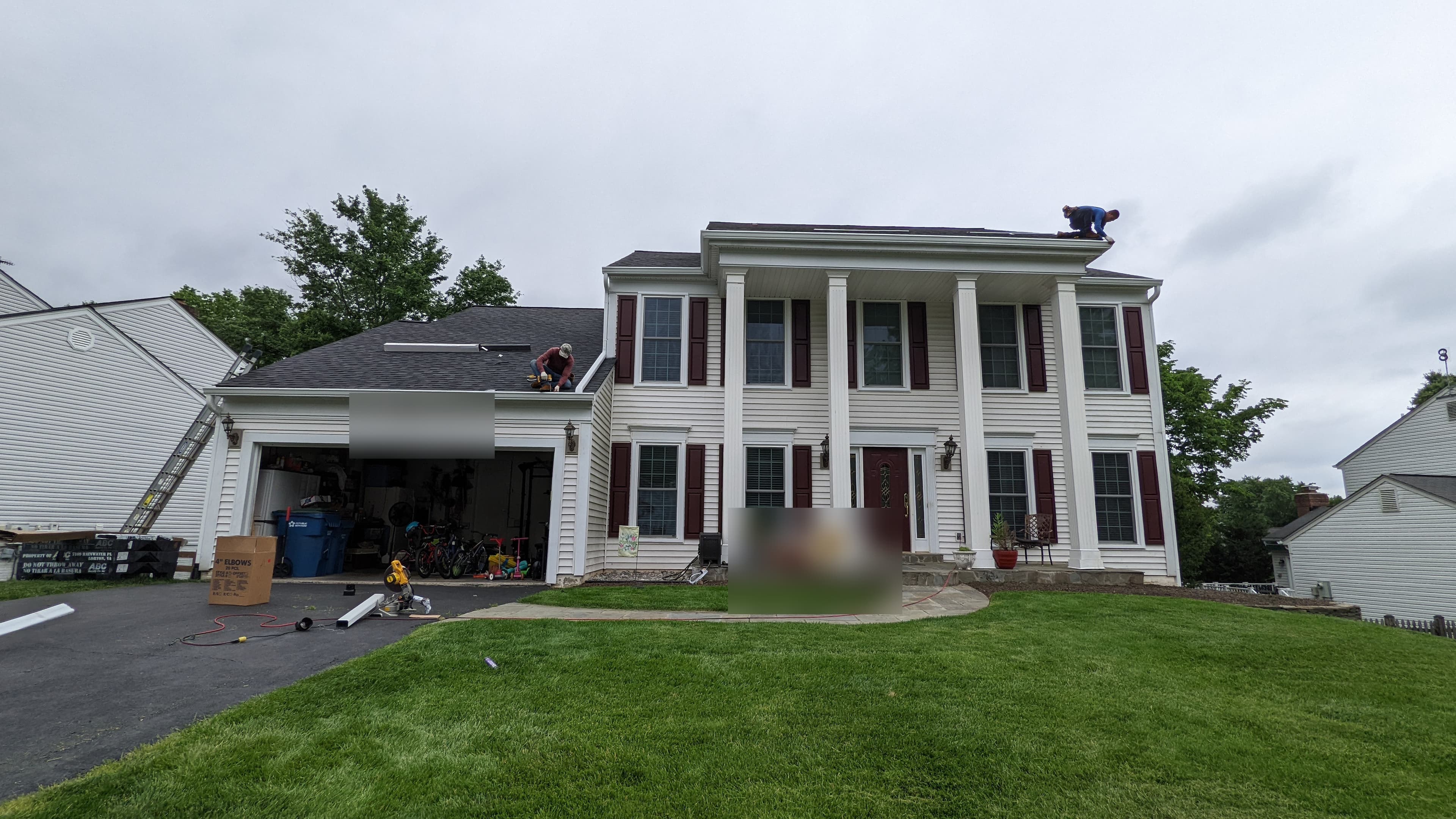 Roofers working on a two-story colonial home during a full roof replacement in Sterling