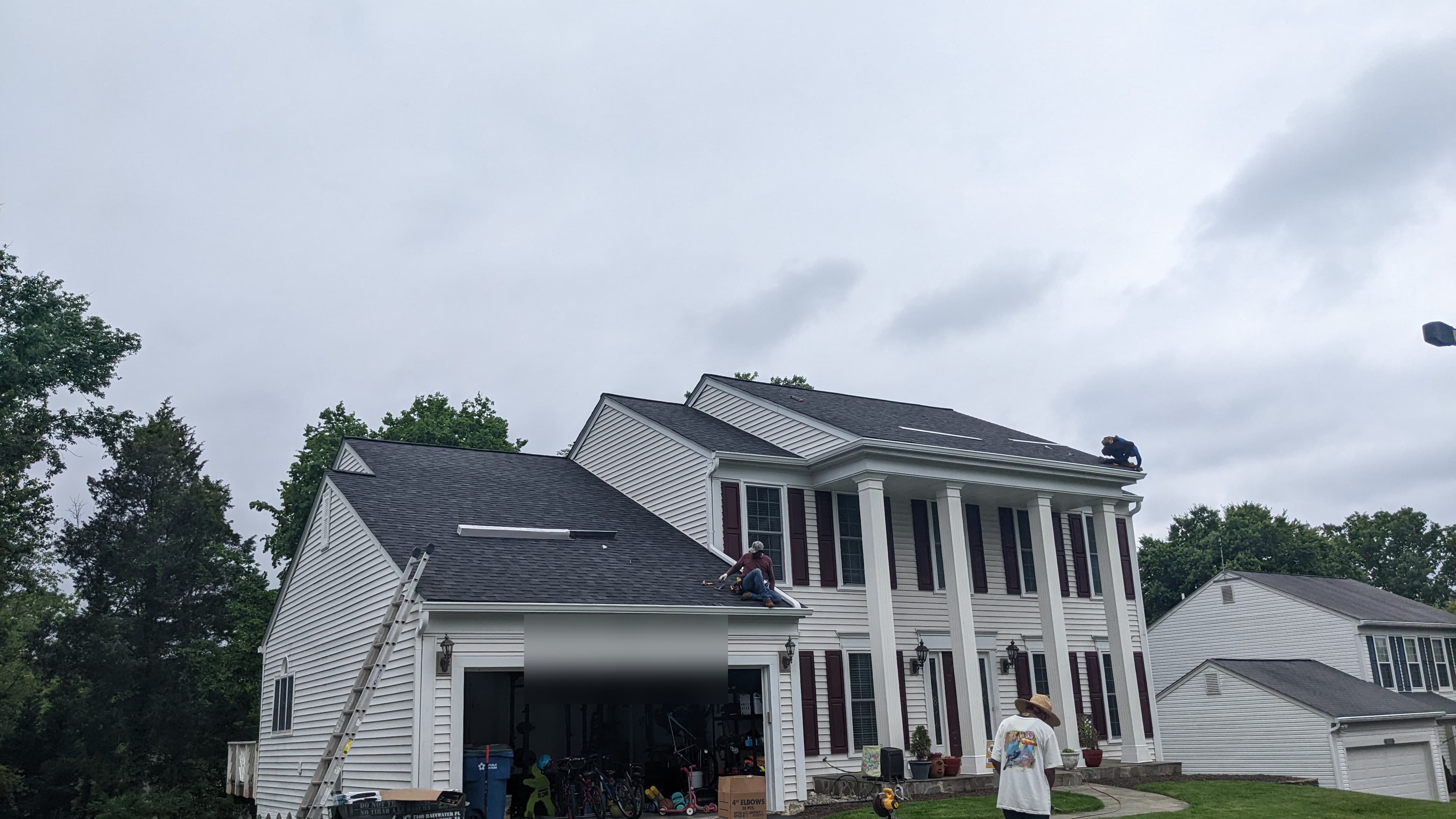Wide view of a two-story colonial home mid-roof-replacement in Sterling